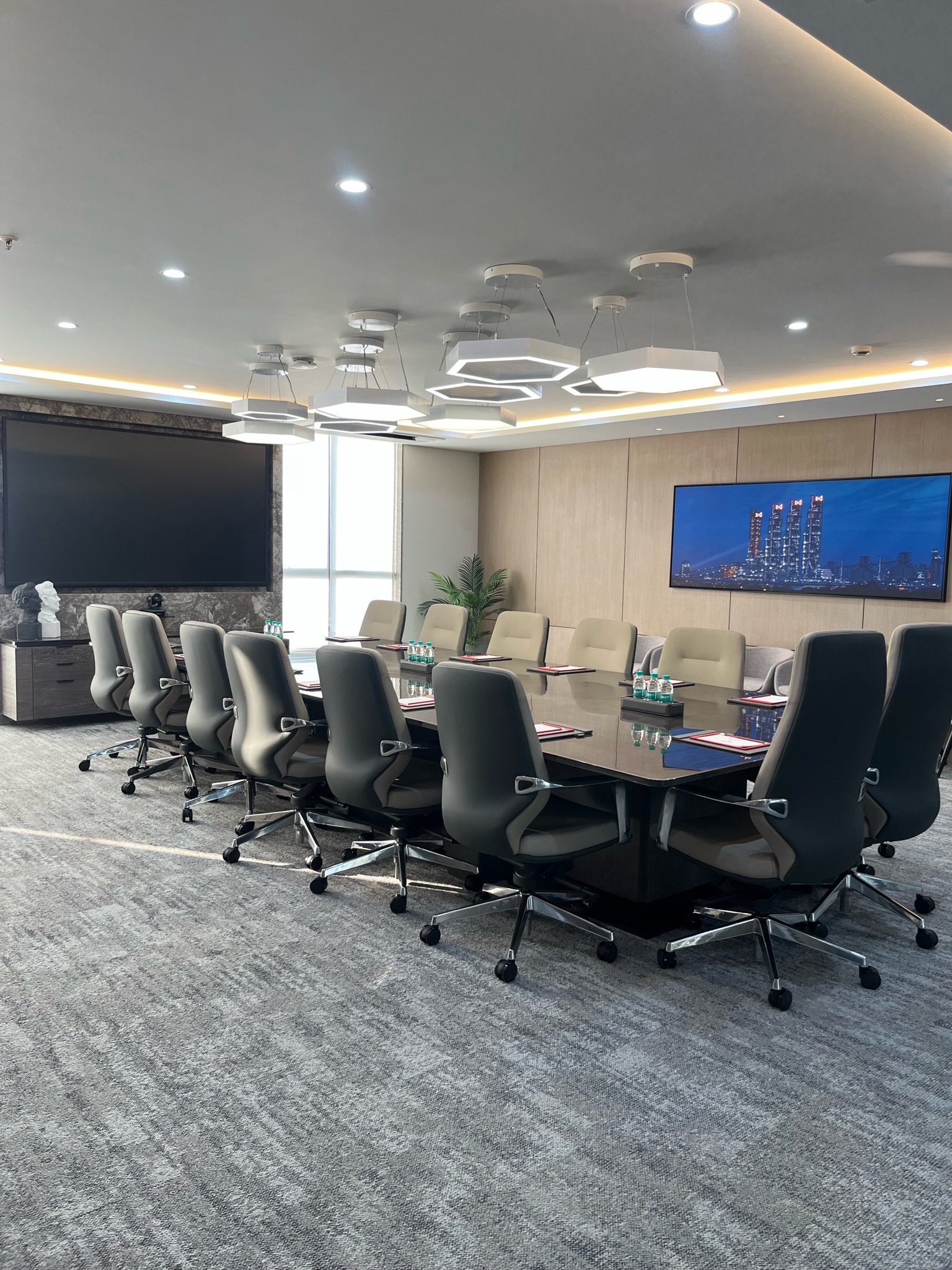 Executive boardroom with hexagonal pendant lighting and skyline art